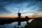 Noctilucent clouds over the dutch landscape with windmill along a canal. A midsummer night fire ritual is held in the distance