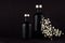 Noir exquisite home decor with blank black cosmetics bottles, white small flowers on dark wood board, mock up.