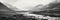 A noir panoramic view of hills and a river with mist