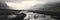 A noir panoramic view of hills and a river with mist