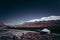 Nomadâ€™s tent, snow-capped mountains in the distance, blue sky and red rock mountains, a grassland in the valley