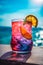 Non-alcoholic summer cocktail with a beach and sea on a background. Summer refreshing drink concept. Generated AI
