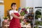 Non binary man florist make photo to flowers by smartphone at flower shop