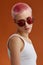 Nonconformist girl with pink short hairs with red sunglasses, over brown background