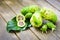 Noni fruit with noni slice and blossom on old wooden table.