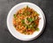 Noodle with pasta, meat, sauce and herbs in a white plate on a dark background, Asian cuisine