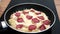 Noodles covered with cheese and slices of raw smoked sausage are fried in a pan. Quick snack
