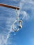 Noose from rope is suspended on gallows against blue sky with clouds