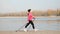 Nordic Walking concept. Young chubby female training with sportive poles along city river and park.