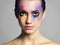 Because normal is just boring. Studio shot of an attractive young woman with brightly colored makeup against a gray