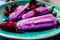 Normal view of a Lollipop style grape ice cream on a stick on a vintage plate on a light blue wooden table. Concept of natural and