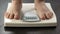 Normal weight, woman standing on scales to check diet results, front view