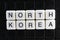 North Korea white text word on black cover. Text word crossword. Alphabet letter blocks game texture background.