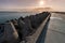 North pier with breakwaters, sunset seascape. Tetrapods along edges of pier. Beautiful evening seascape. Modern lighthouse in