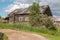 North Russian village Isady. Summer day, Emca river, old cottages on the shore, old wooden bridge. Abandoned building.