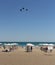 Northen beach in Burgas city, people on the beach below the sun umbrellas, Black sea in the background, flying birds, blue sky.