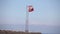 Northern Cyprus, the flag of the Republic of Northern Cyprus against the blue sky and the sea