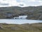 Northern landscape, tundra in Swedish Lapland with blue artic lake with reamains of melting snow cave, green hills and