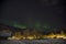 The northern lights aurora borealis rising behind a mountain in a small village in the north of Norway. In the middle of winter