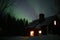 Northern lights over illuminated Swedish wood house