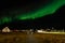 Northern lights and starlight sky over the settlement with living houses and road, Nuuk, Greenland