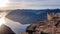 Norway - A girl standing at the edge of Preikestolen during the sunset