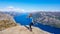 Norway - Girl standng on a steep cliff with the view on Lysefjorden