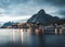 Norwegian fishing village Reine at the Lofoten Islands in Norway. Dramatic sunset clouds moving over steep mountain