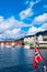 Norwegian flag on the background of the bay and the old wooden houses on the waterfront of Bergen