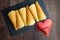 Norwegian Krumkake cookies on a slate plater, rustic dark wood background, red metal heart