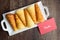 Norwegian Krumkake cookies on a white ceramic plater, rustic dark wood background, red note to Santa