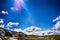 Norwegian mountains, big dark blue sky with sun rays, white clouds. Small woman figure goes along the horizon