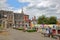 NORWICH, UK - JUNE 4, 2017: People relaxing at Memorial Gardens overlooking colorful market stalls and with the Guildhall in the b