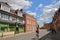 NORWICH, UK - JUNE 4, 2017: A young redhead woman cycling on Bethel street with colorful and medieval houses and a beautiful sky