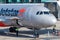 Nose of Airbus A320 docked at terminal gate on tarmac at Brisbane air port with man operating open hatch to unload luggage