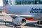 Nose of Airbus A320 docked at terminal gate on tarmac at Brisbane air port with workman beneath plane