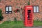 Nostalgic phone box in front of red brick wall with rambler rose