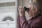 Nosy neighbor looking through window with binoculars on a rainy day