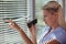 Nosy woman peering through some blinds