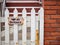 Not an entrance sign on white picket fence with rusted parts on brick building