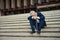 Not his best day. a dejected businessman sitting on the stairs outside his office with his head in his hands.