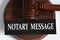 NOTARY MESSAGE - words on a black sheet against the background of a judge\\\'s gavel