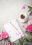 Note book, peonies and cup of coffee on light concrete backgrounds