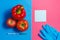 Note, Green Liquid in Syringe, Red Tomato, Apple, Pepper, Blue Gloves. Genetically Modified Food Concept on Pink Blue.