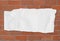 Note white ripped paper on brick red background