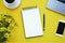 Note on yellow background with phone, flowers, coffee and laptop. Copy space.
