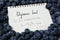 Notebook with calculated glycemic load for blueberries surrounded by fresh berries, closeup