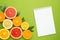 Notebook and citruses fruits on green background, fruit flatlay, summer minimal compositon with grapefruit, lemon, mandarin and