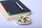 Notebook and colorful assortment pills, capsules on plate.