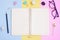 Notebook ,Eyeglasses,Black pencil,Eraser,Paper Clips and White Flower on Pink,Yellow and Blue Background